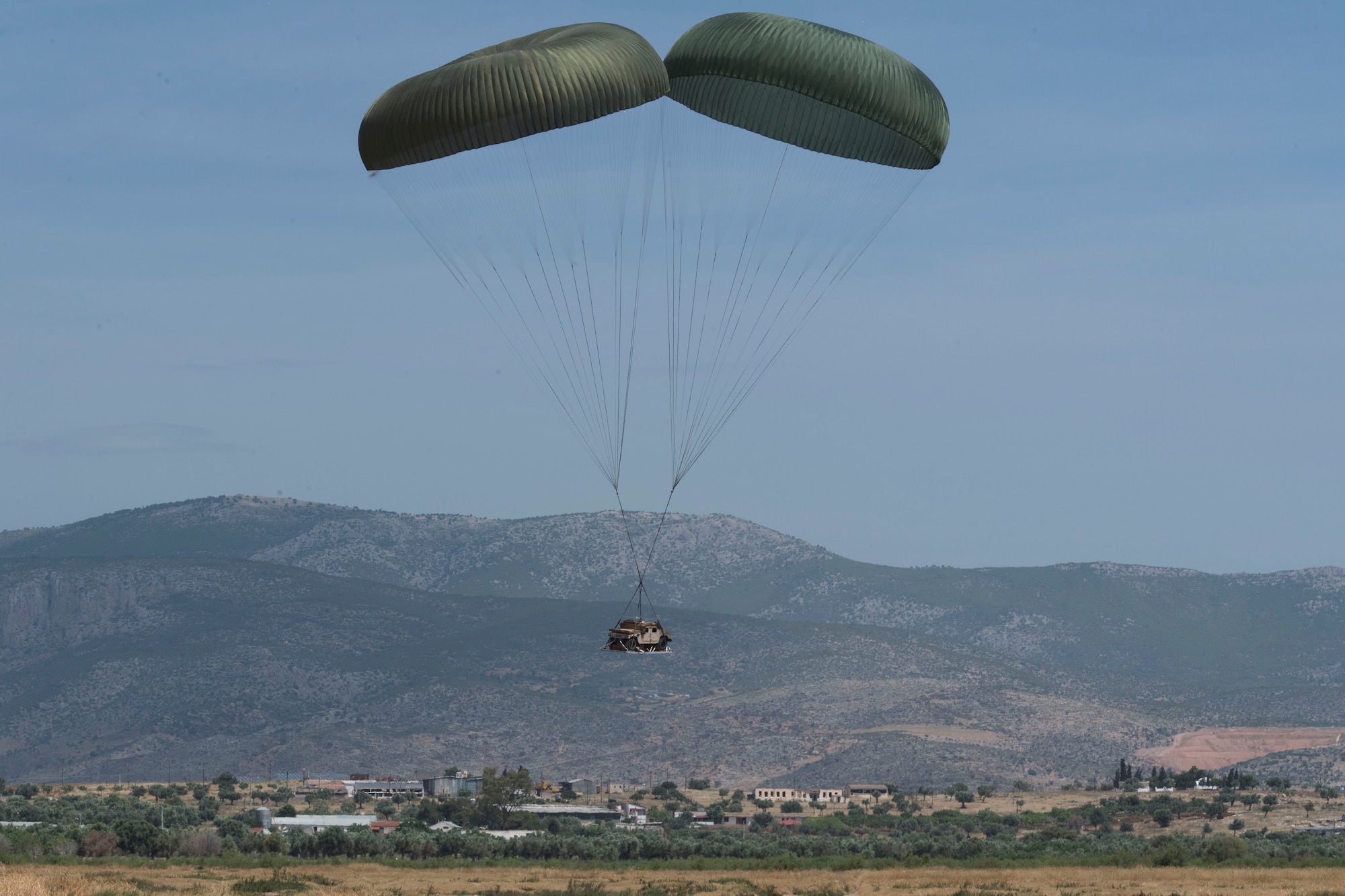 A U.S. Humvee rigged to parachutes floats to the ground during an exercise Stolen Cerberus V training mission over Megara Drop Zone, Greece, May 15, 2018. Hellenic riggers worked with U.S. Air Force joint airdrop inspectors to get the Humvee properly rigged to drop. (U.S. Air Force photo by Senior Airman Devin M. Rumbaugh)