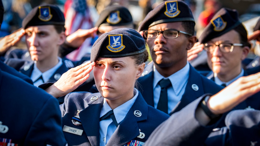 Airmen salute while standing in formation.