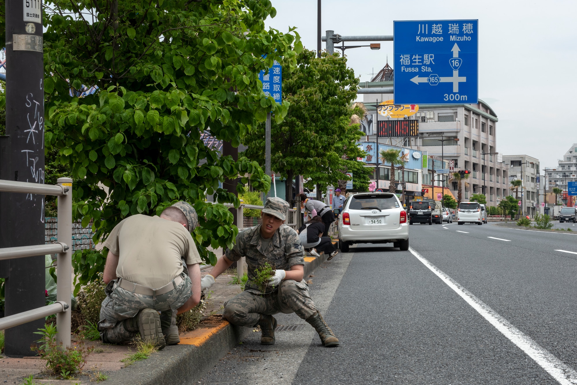 Senior Airman Amy Kristoffersen, 374th Communications Squadron Operations Flight client systems technician journeyman, pulls weeds from a tree bed during the Fussa Beautification Project outside of Yokota Air Base, Japan in Fussa May 17, 2018.