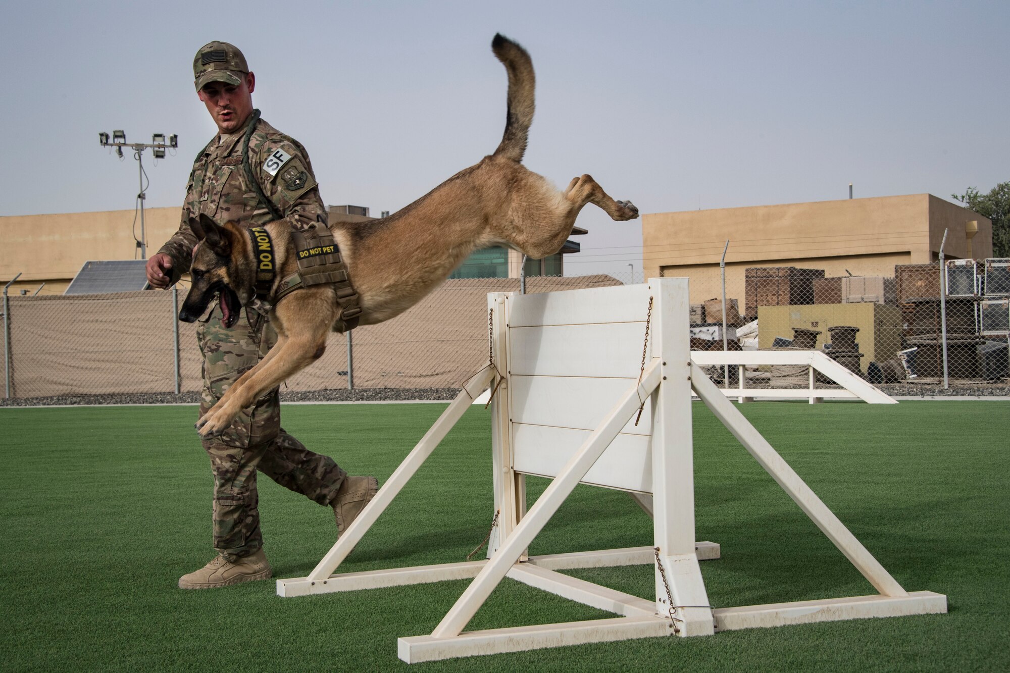 U.S. Air Force Staff Sgt. Cody Howey, 380th Security Forces Squadron military working dog han-dler and his K-9 partner, Eros, navigate an obstacle during a warm-up exercise to prepare Eros for patrol duty on Al Dhafra Air Base, United Arab Emirates, May 14, 2018. (U.S. Air National Guard photo by Tech. Sgt. Nieko Carzis)