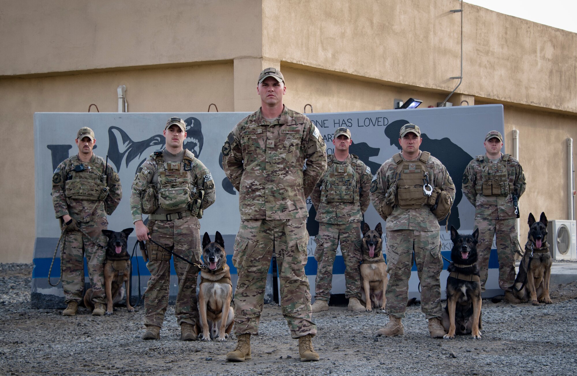 From left to right: U.S. Air Force Military Working Dog Handlers Staff Sgt. Brandon Ouderkirk, Staff Sgt. Carmen Pontello, Staff Sgt. Jeffrie Kennedy, Staff Sgt. Cody Howey, Staff Sgt. Dustin Reed, and Staff Sgt. Patrick Cushing pose for a group photo with their military working dogs, Kon-ga, Max, Eros, Szuli, and Tuko at the 380th Air Expeditionary Squadron K-9 facility, Al Dhafra Air Base, United Arab Emirates, May 15, 2018. (U.S. Air National Guard photo by Tech. Sgt. Nieko Carzis)