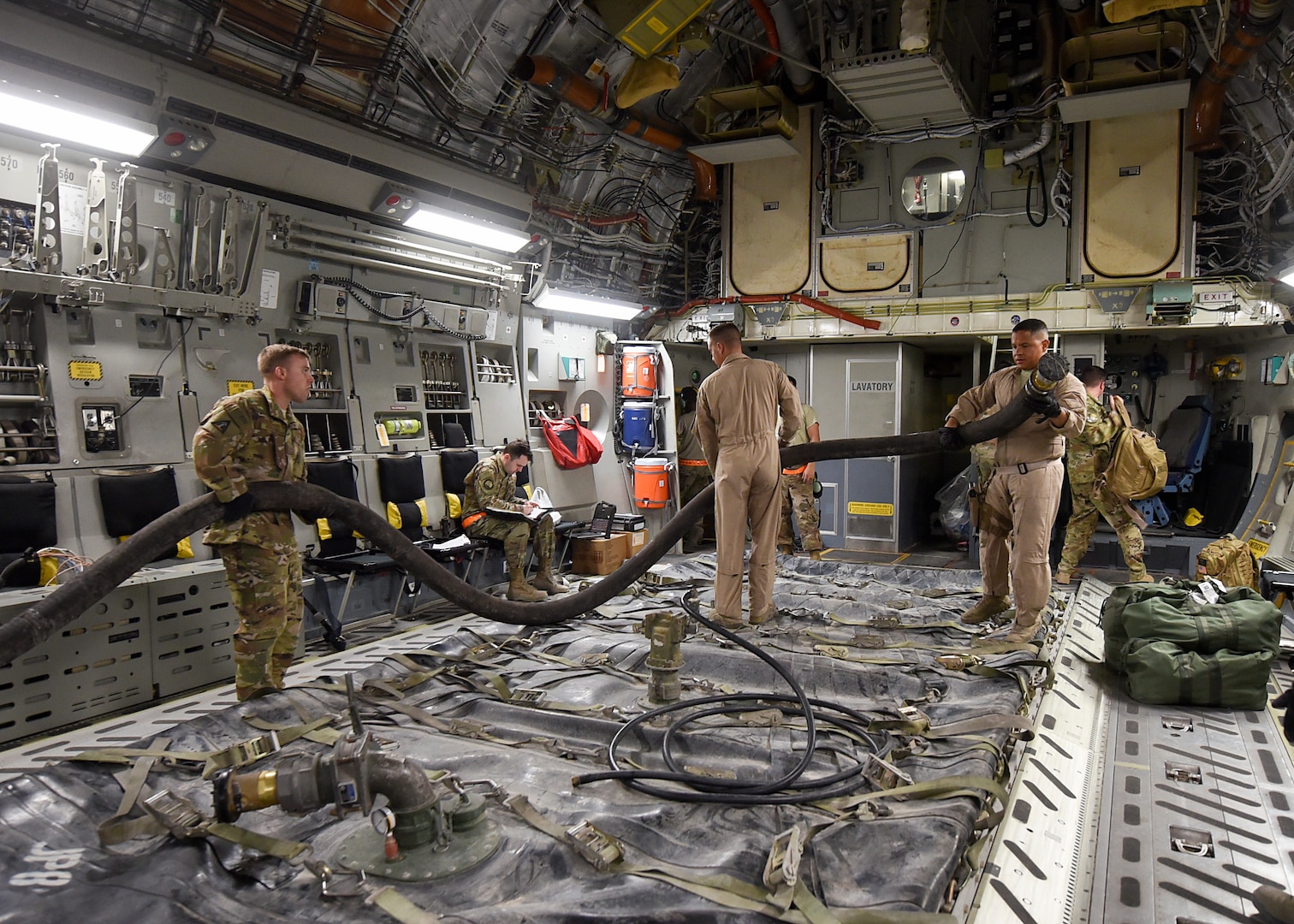 Members of the 379th Expeditionary Logistics Readiness Squadron, Fuels Management Flight, realigns a hose above an empty fuel bladder at Al Udeid Air Base, Qatar, May 11, 2018. This delivery is the first of its kind in more than a year and a half. (U.S Air Force photo by Staff Sgt. Enjoli Saunders)