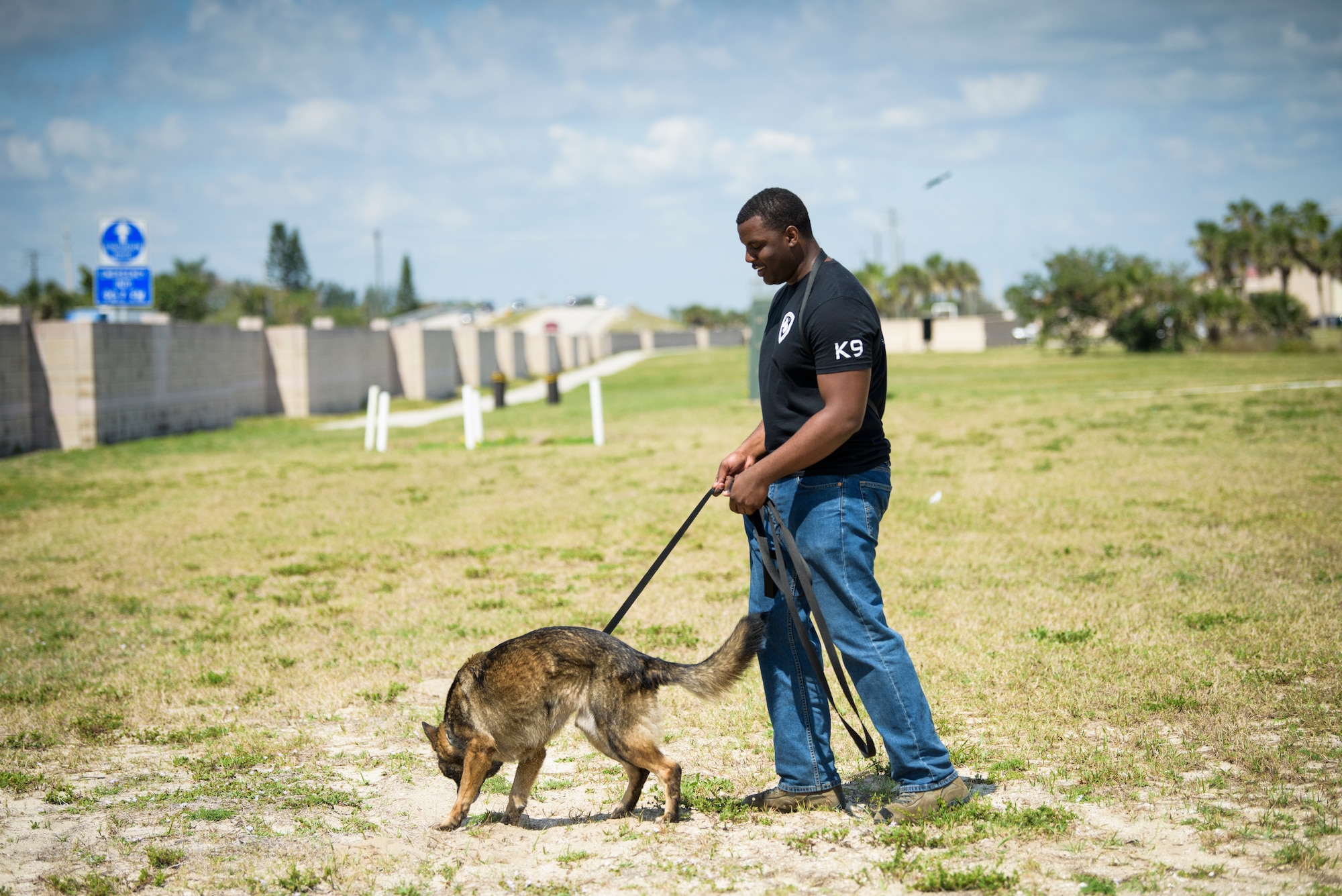 Senior Airman Antoine Carr, future military working dog handler, watches as MWD Dome does a sweep for explosive materials April 26, 2018 at Patrick Air Force Base, Fla. Carr, until his own MWD returns froma deployment, trains with other handler's dogs – but says he can't wait for the day that he can go on patrols, do sweeps and just enjoy the company of his own dog. (U.S. Air Force phot by Airman 1st Class Zoe Thacker)