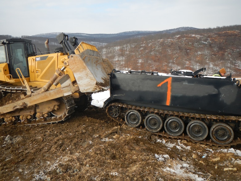 A bulldozer pushes a 13-ton M106 mortar carrier into position on Cranberry Mountain near West Point, New York, during winter as part of an ongoing project to emplace heavy targets on the post’s indirect-fire range.