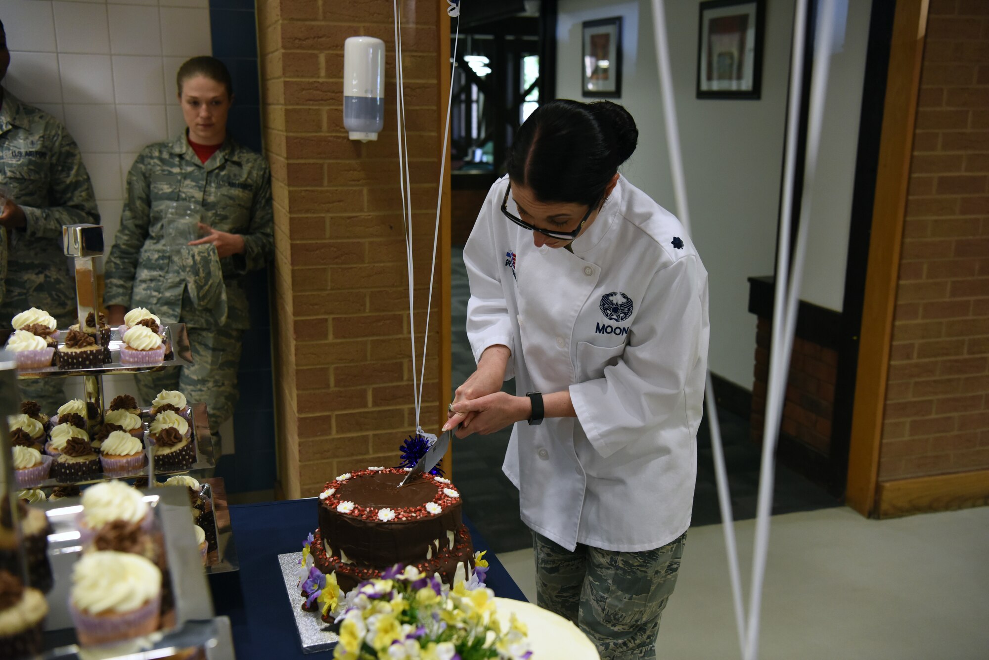 Lt. Col. Kelli R. Moon, commander of the 48th Force Support Squadron, cuts a cake at the Knight's Table Dining Facility as part of the 48th Force Support Squadron's "You Got Served" events at Royal Air Force Lakenheath, England, May 18, 2018. The Knight's Table Dining Facility held a Royal Wedding cake cutting event for dining facility patrons. (U.S. Air Force Photo/ Airman 1st Class John A. Crawford)
