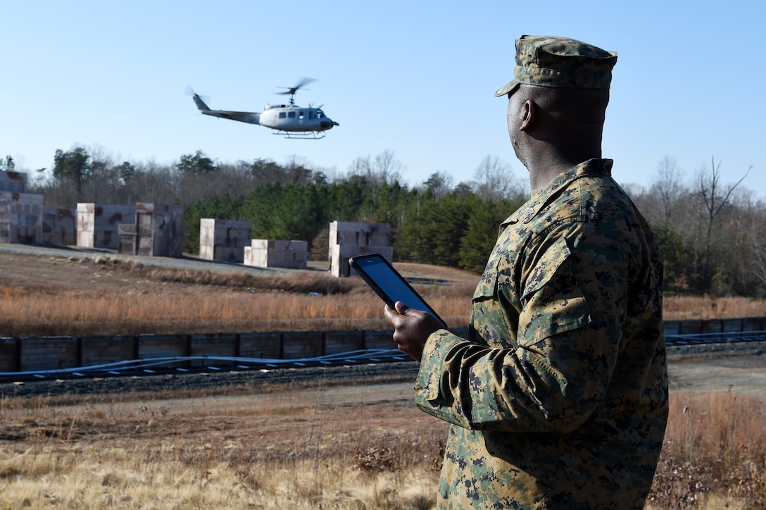 Marine Corps Sgt. Dionte Jones watches as an UH-1 “Huey” helicopter equipped with the Office of Naval Research-sponsored Autonomous Aerial Cargo Utility System kit departs the landing zone following a resupply mission he requested using a handheld tablet at Marine Corps Base Quantico, Va.