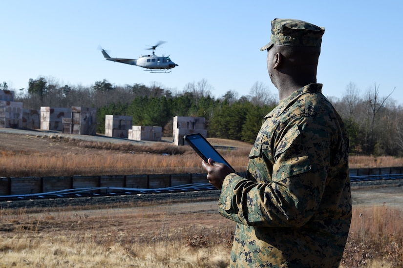 Marine Corps Sgt. Dionte Jones watches as an UH-1 “Huey” helicopter equipped with the Office of Naval Research-sponsored Autonomous Aerial Cargo Utility System kit departs the landing zone following a resupply mission he requested using a handheld tablet at Marine Corps Base Quantico, Va.