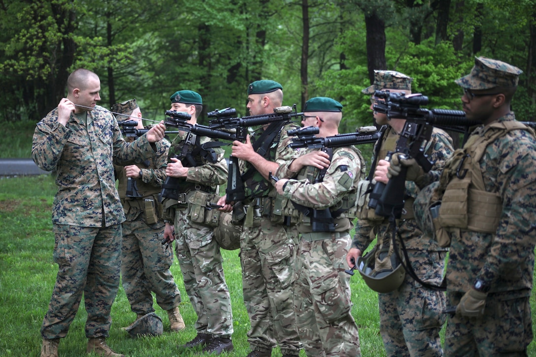 Marines and British commandos stand together holding guns during a military exercise.