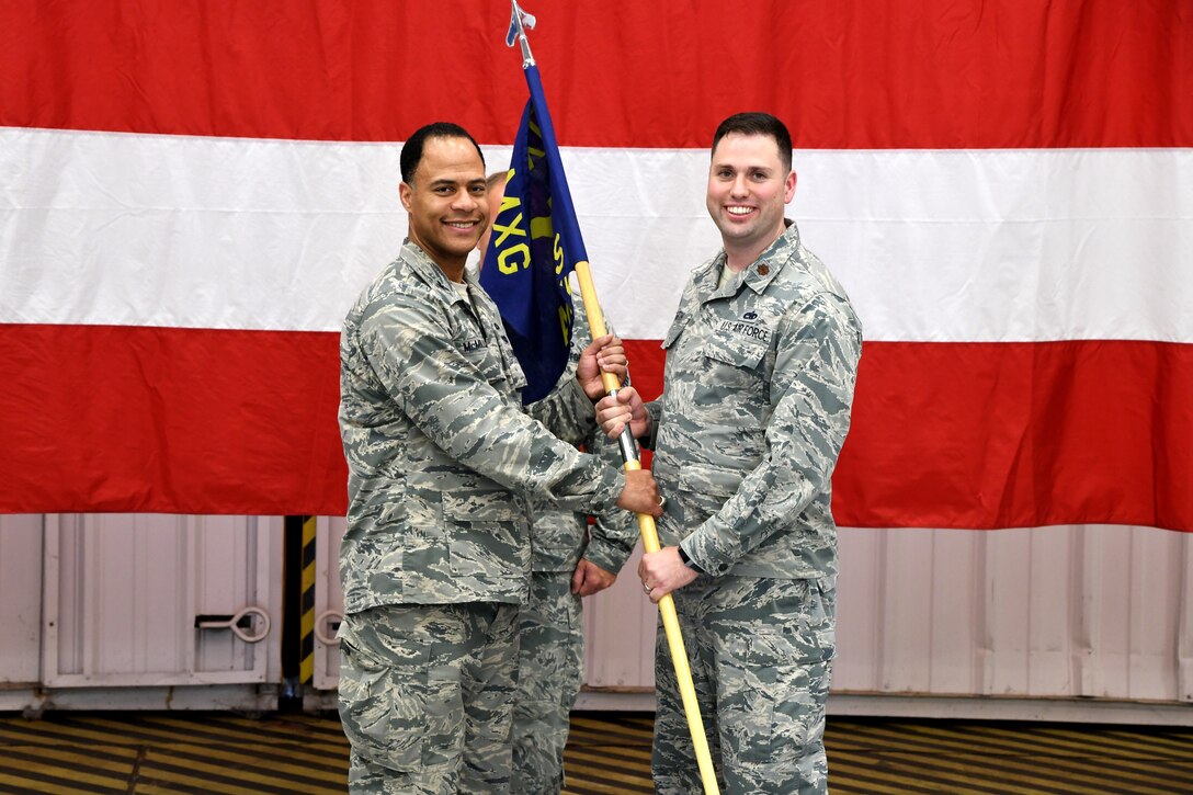 Col. André A. McMillian, 94th Maintenance Group commander, passes the 94th MXG guidon to Maj. Wade Smith during an assumption-of-command ceremony at Dobbins Air Reserve Base, Ga. on May 5, 2018. Smith formally assumed command of the 94th Aircraft Maintenance Squadron during the event. (U.S. Air Force photo/Senior Airman Josh Kincaid)