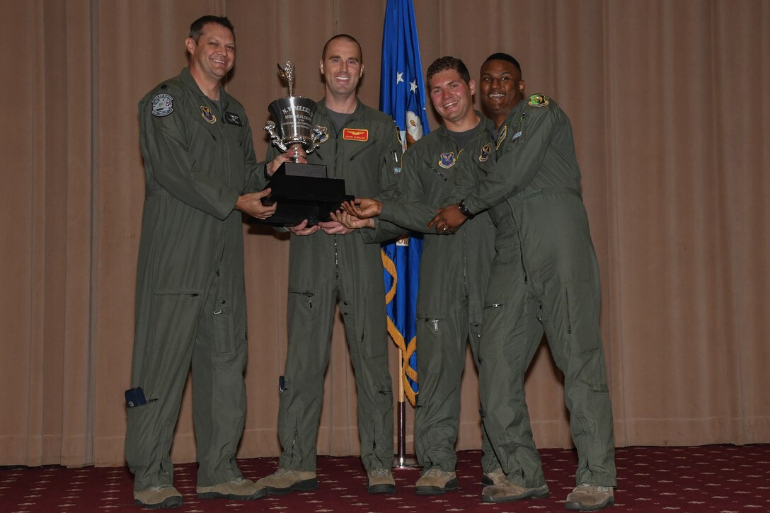 Lt. Col. William Fish, the commander of the 11th Bomb Squadron, presents the Meeks Award to Capt. Shane McMillen, 1st Lt. Mitchell Redmond and 1st Lt.  Zaquero Harnett during a graduation ceremony on Barksdale Air Force Base, La. May 18, 2018.