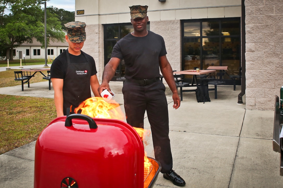 Cpl. Demetrius Gray, right, prepares his grill for the Pit Masters cook off aboard Marine Corps Air Station Beaufort May 16. Each team prepared a plate of BBQ samples for the judges. The competition served to foster camaraderie and sharpen the skills of food service Marines and Sodexo workers. Demetrius and Cpl. Jamie Dang are food service specialists with Headquarters and Headquarters Squadron.