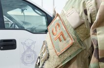A 380th Security Forces member wears a career field patch in front of a security forces vehicle receiving a foreign object debris check at Al Dhafra Air Base, United Arab Emirates, May 17, 2018. (U.S. Air National Guard photo by Staff Sgt. Ross Alexander Whitley)