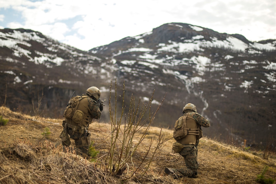 Marines fire their weapons at targets from a kneeling position.