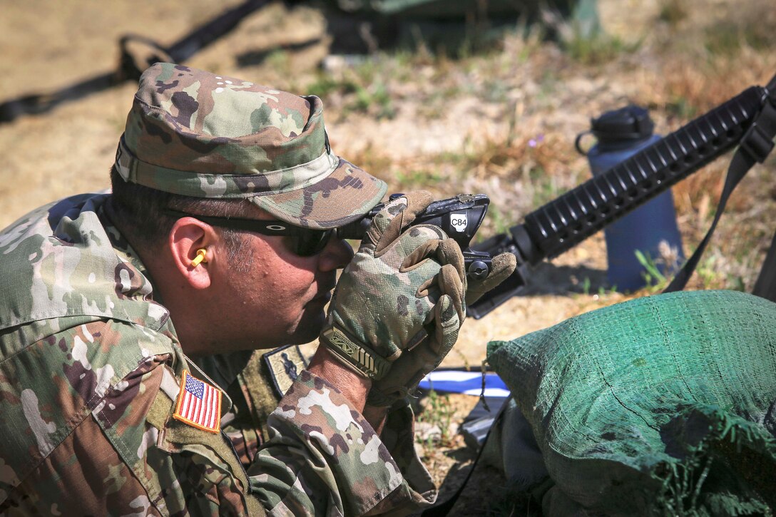 A soldier looks through a scope at 300-meter targets.