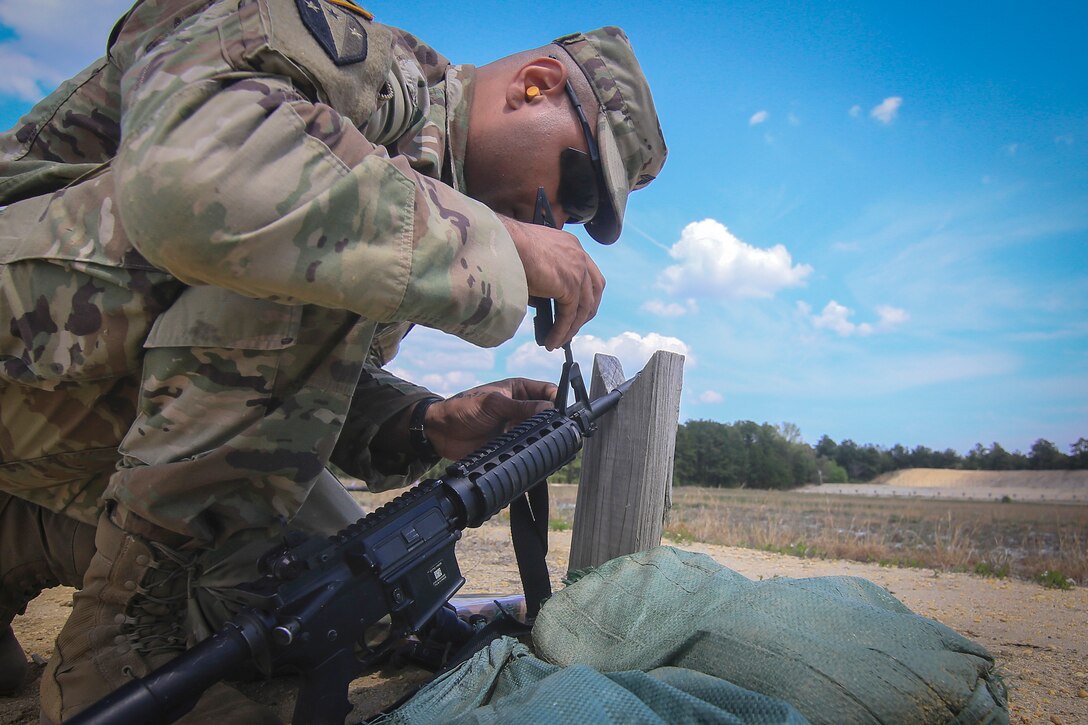 A soldier makes sight adjustments on his M-4 Carbine.