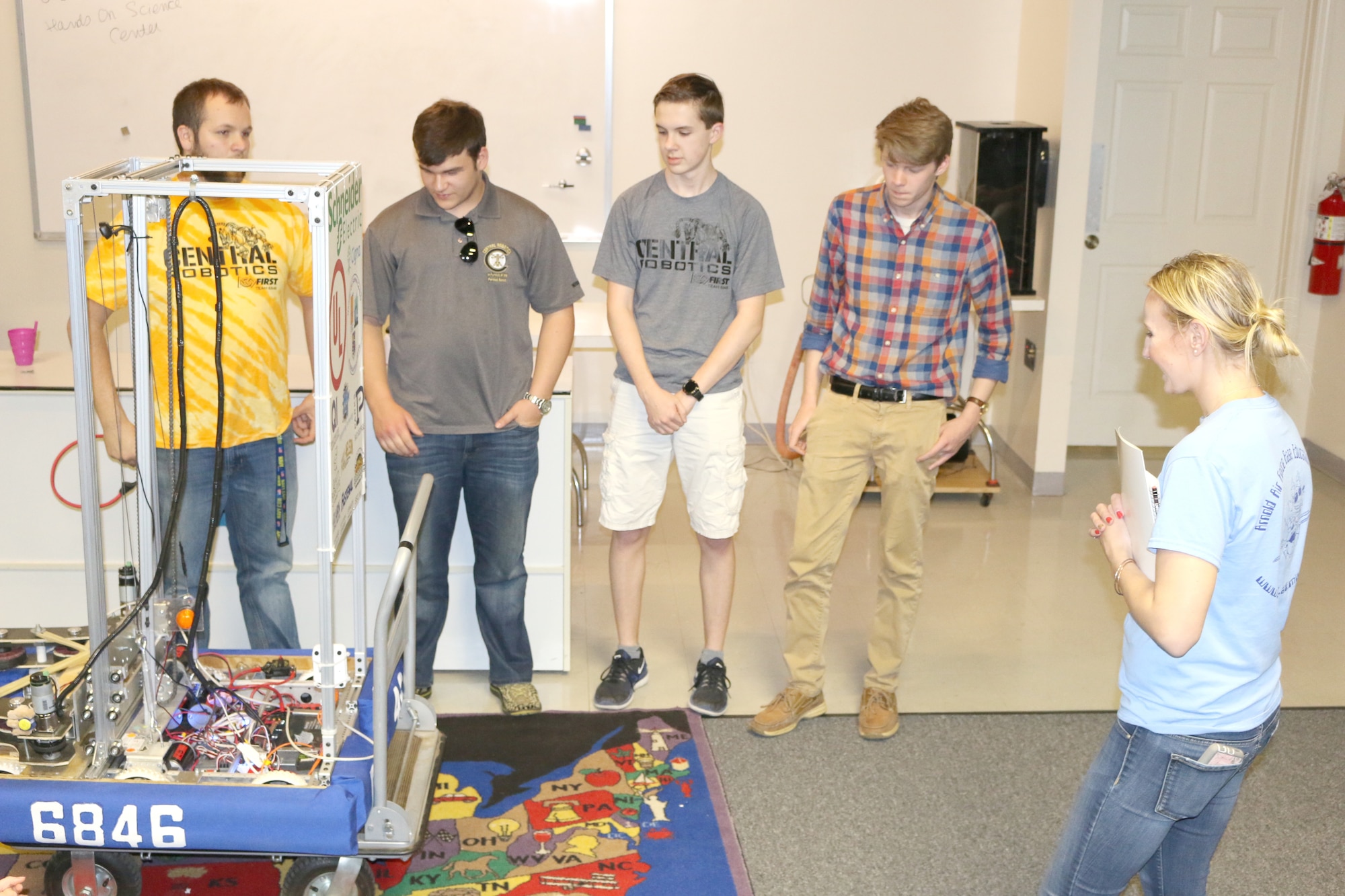 Olga Oakley, the Hands-On Science Center Air Force STEM director, at right standing, asks the Central Magnet Robotics team about their trip to the FIRST® Robotics World Championship in Houston, Texas. The Central Magnet Robotics team visited the HOSC in Tullahoma May 1 to give a demonstration. Pictured, starting left standing, are Aidan Gibson, Jimmy Jones, David Schafer, Drew Dove, Marc Guthrie, Olga Oakley, Maddy Perrien and Ethan Davenport. (U.S. Air Force photo/Deidre Ortiz)