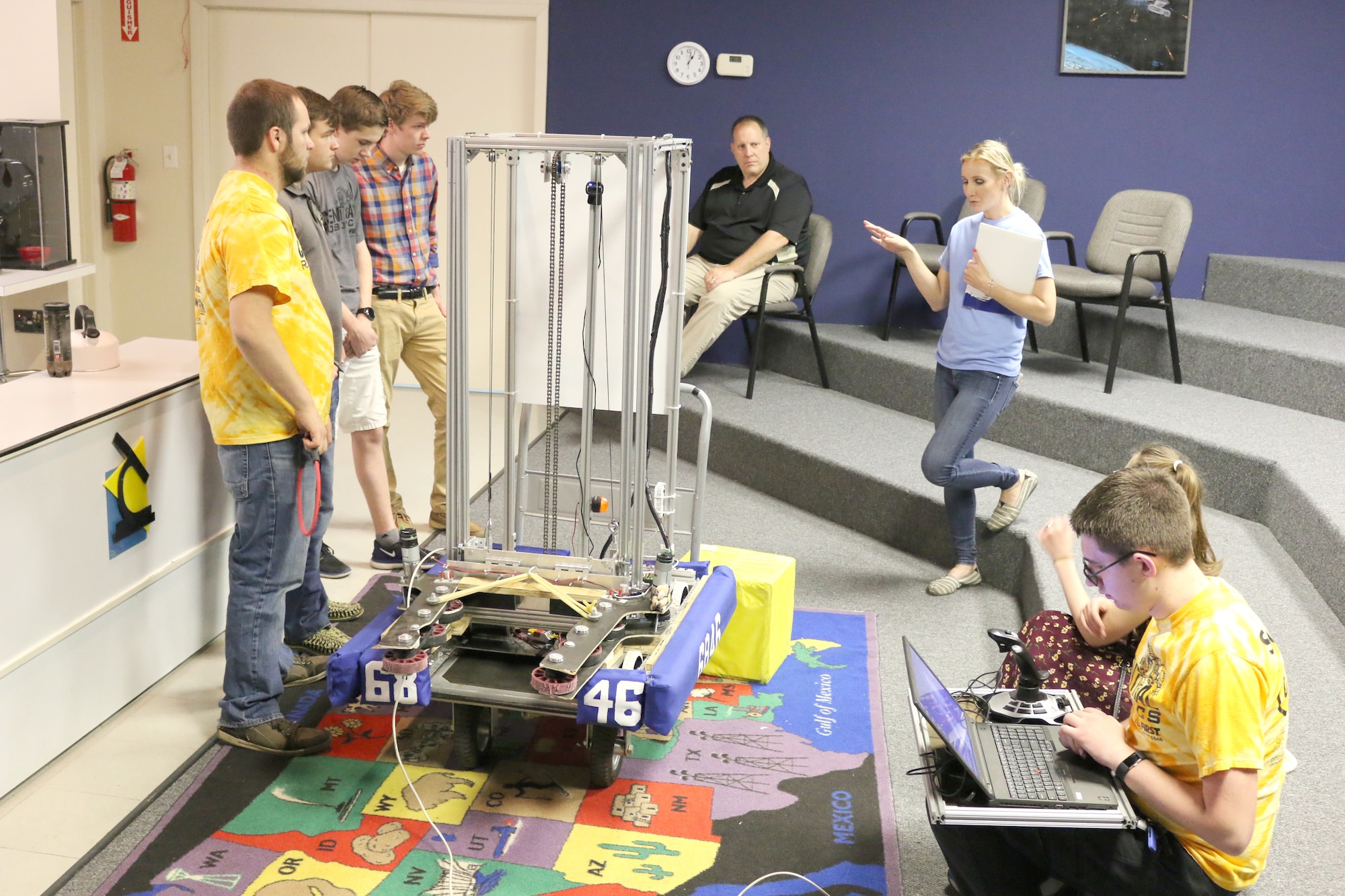 Olga Oakley, the Hands-On Science Center Air Force STEM director, at right standing, asks the Central Magnet Robotics team about their trip to the FIRST® Robotics World Championship in Houston, Texas. The Central Magnet Robotics team visited the HOSC in Tullahoma May 1 to give a demonstration. Pictured, starting left standing, are Aidan Gibson, Jimmy Jones, David Schafer, Drew Dove, Marc Guthrie, Olga Oakley, Maddy Perrien and Ethan Davenport. (U.S. Air Force photo/Deidre Ortiz)