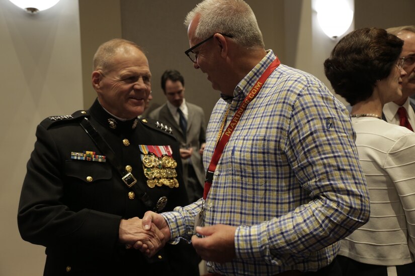 Mark Rosen, the head volleyball coach at the University of Michigan, gives a school coin to Marine Corps Commandant Gen. Robert B. Neller during an evening parade reception as part of Marine Corps Recruiting Command’s 2018 Coaches Workshop at Marine Corps Barracks in Washington, D.C.