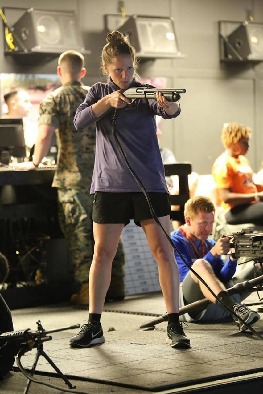 Maddy Evans, the assistant soccer coach at West Chester University of Pennsylvania, fires a shotgun using the marksmanship simulator during Marine Corps Recruiting Command’s 2018 Coaches Workshop at Marine Corps Base Quantico, Va.