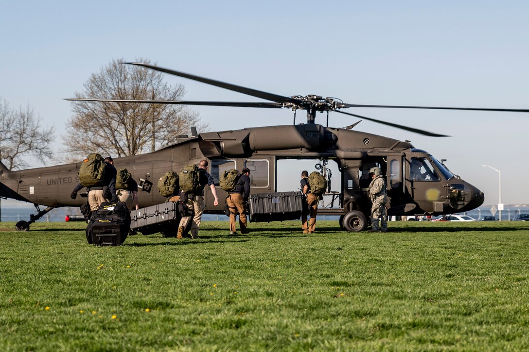 Soldiers and airmen load gear onto a helicopter.