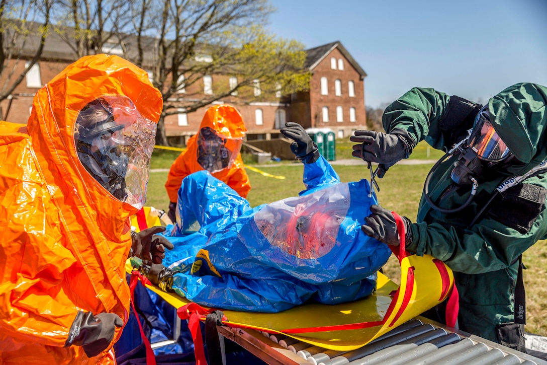 An airman cuts away a team members suit.