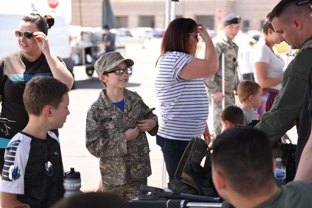 Conor Hutton, center, the son of Heather, far left, and U.S. Air Force Senior Airman Michael Hutton, 460th Security Forces Squadron patrolman, learns about the safety equipment worn by defenders during a Police Week demonstration at Buckley Air Force Base, Colorado, May 17, 2018.