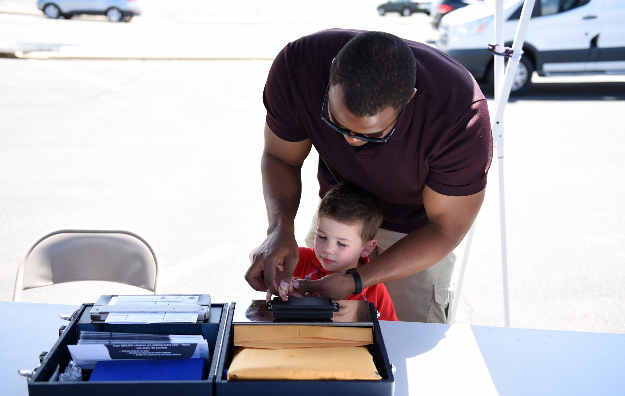 U.S. Air Force Tech. Sgt. Antonio Burton, 460th Security Forces Squadron investigator, provides fingerprints for Connor Collier, the son of Heather and Tech. Sgt. Bryan Collier, 460th SFS visitor center NCO in charge, as part of a Police Week demonstration at Buckley Air Force Base, Colorado, May 17, 2018.