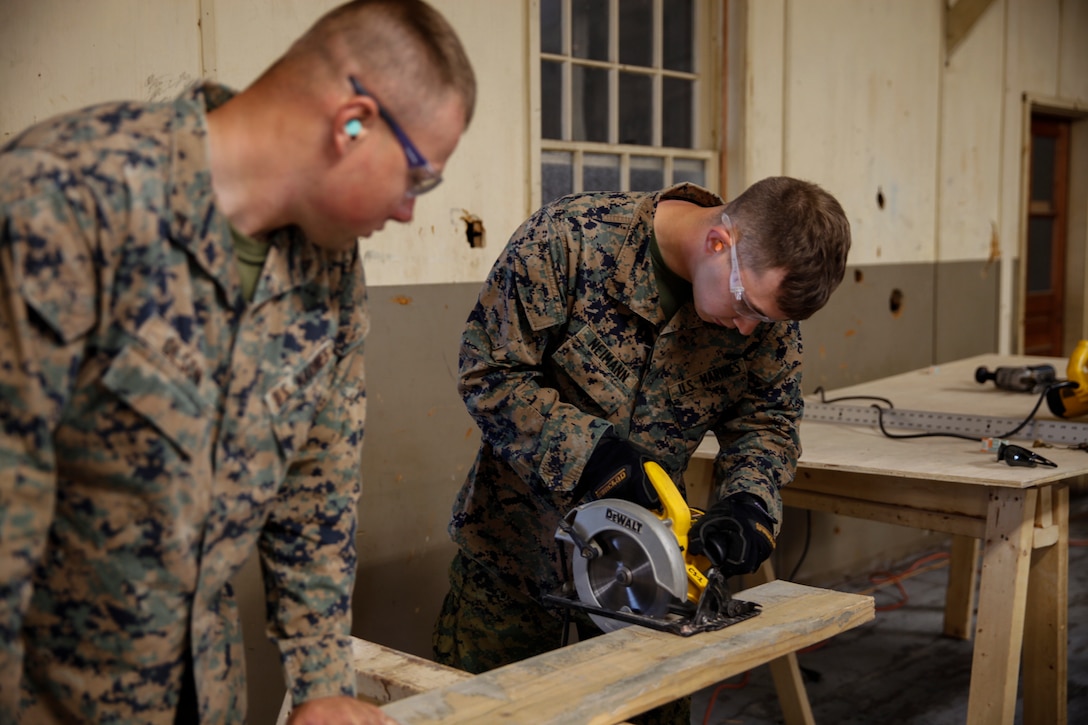 U.S. Marine Lance Cpl. Mitchell R. Neimann (right), heavy equipment operator with Engineer Company C, 6th Engineer Support Battalion, 4th Marine Logistics Group, uses a circular saw to practice cutting a wooden plank as U.S. Marine Cpl. Evan A. Olsen (left), motor vehicle mechanic with ECC, 6th ESB, 4th MLG, holds the wood in place at a construction site during exercise Red Dagger at Fort Indiantown Gap, Pa., May 19, 2018.