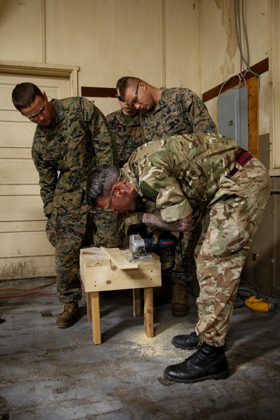 British Army Cpl. Jonathan Evans, commando with 131 Commando Squadron Royal Engineers, British Army, practices cutting plywood with a jig saw power tool while Marines with 6th Engineer Support Battalion, 4th Marine Logistics Group, watch his technique at a construction site during exercise Red Dagger at Fort Indiantown Gap, Pa., May 19, 2018.