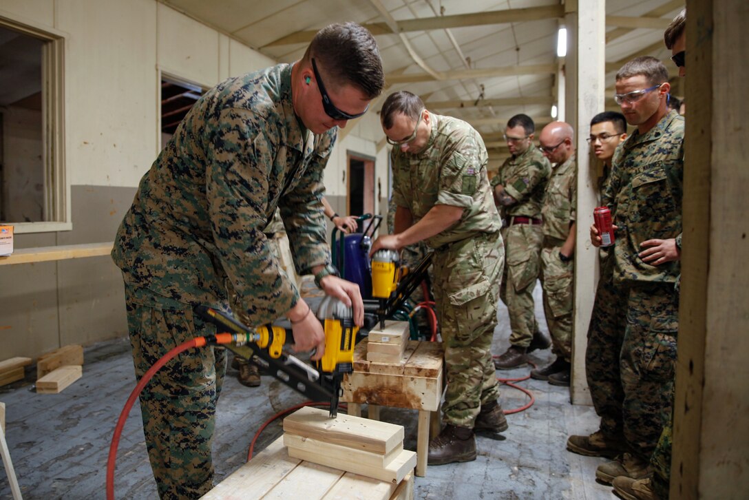 U.S. Marine Lance Cpl. James J. Gresh, motor vehicle operator with Bridge Company B, 6th Engineer Support Battalion, 4th Marine Logistics Group, and British Army Spr. Marc C. Haldron, commando with 131 Commando Squadron Royal Engineers, British Army, practice using nail guns at a construction site during exercise Red Dagger at Fort Indiantown Gap, Pa., May 19, 2018.