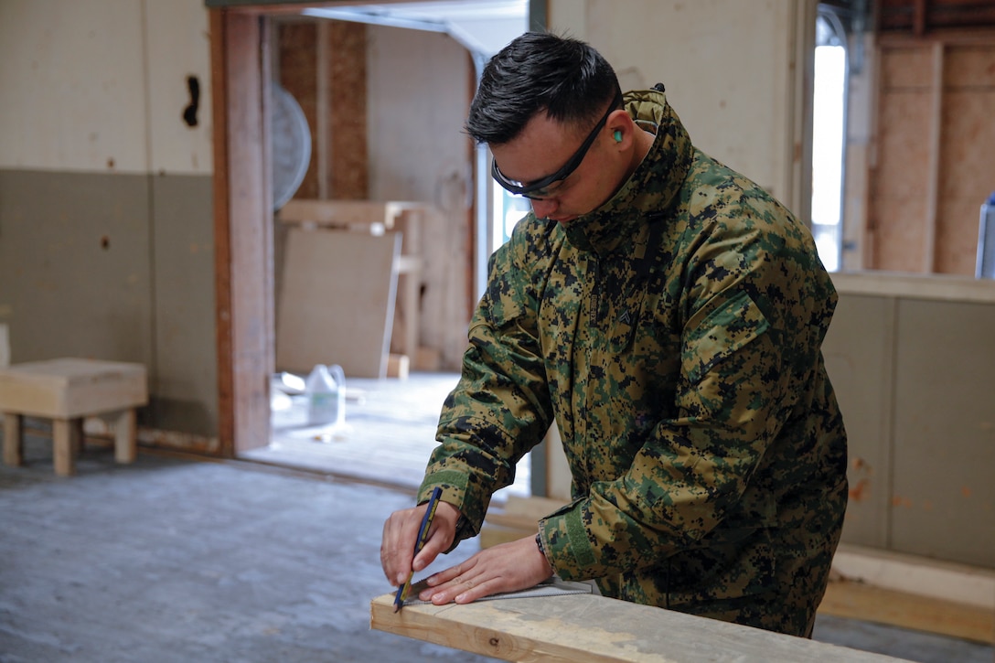 U.S. Marine Cpl. Junior G. Moncayo, heavy equipment mechanic with Bridge Company B, 6th Engineer Support Battalion, 4th Marine Logistics Group, draws a cut line on a wooden plank at a construction site during exercise Red Dagger at Fort Indiantown Gap, Pa., May 19, 2018.