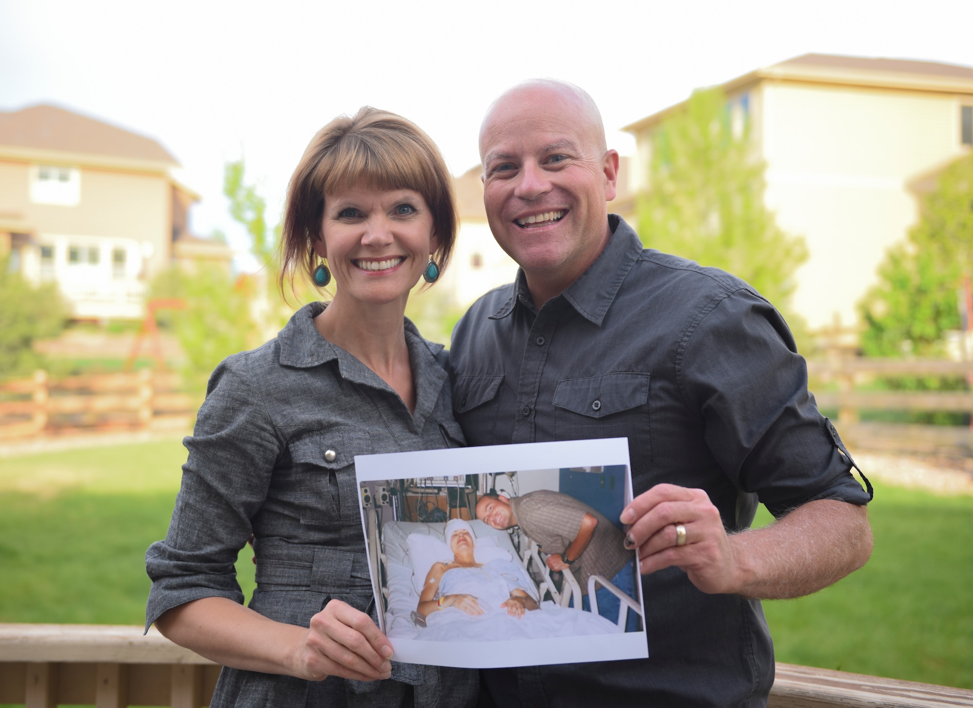 Jodi Novak, left, cancer survivor and Lt. Col. Kneil Novak, 460th Space Wing Command Post chief, pose for a photo May 14, 2018, in Parker, Colorado. The couple displays a photo of themselves during Jodi’s treatment that lasted nearly two years. (U.S. Air Force photo by Airman 1st Class Michael D. Mathews)