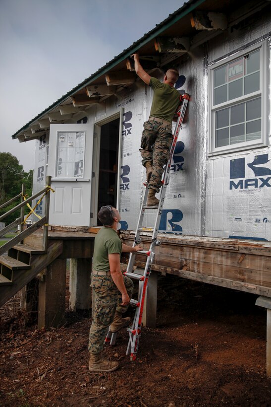 U.S. Marine Private First Class Jeffrey Beasley (top), combat engineer with Engineer Company C, 6th Engineer Support Battalion, 4th Marine Logistics Group, measures a plank while U.S. Marine Lance Cpl. Dylan A. Hudson (bottom), combat engineer with ECC, 6th ESB, 4th MLG, holds the ladder in place at a construction site during exercise Red Dagger at Fort Indiantown Gap, Pa., May 20, 2018.