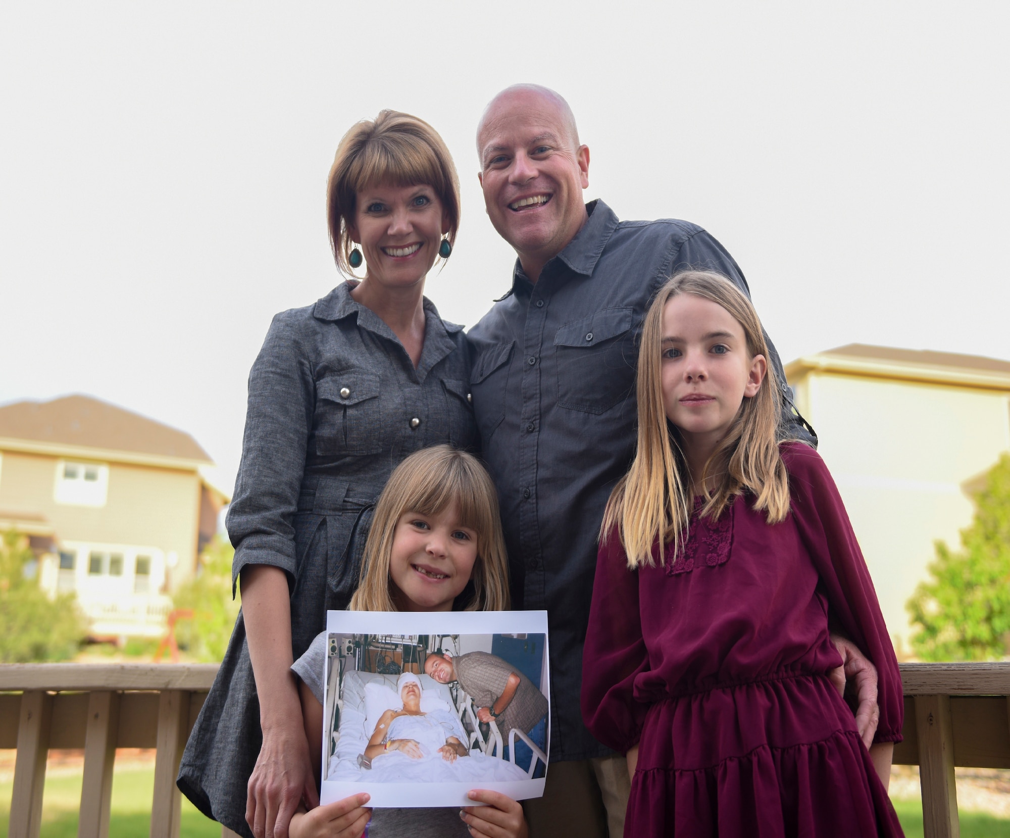The Novak family pose for a photo May 14, 2018, in Parker, Colorado. Bethany is holding up a photo of her parents during Jodi’s treatment. Both Bethany and Abigail believe their mom is a superhero. (U.S. Air Force photo by Airman 1st Class Michael D. Mathews)
