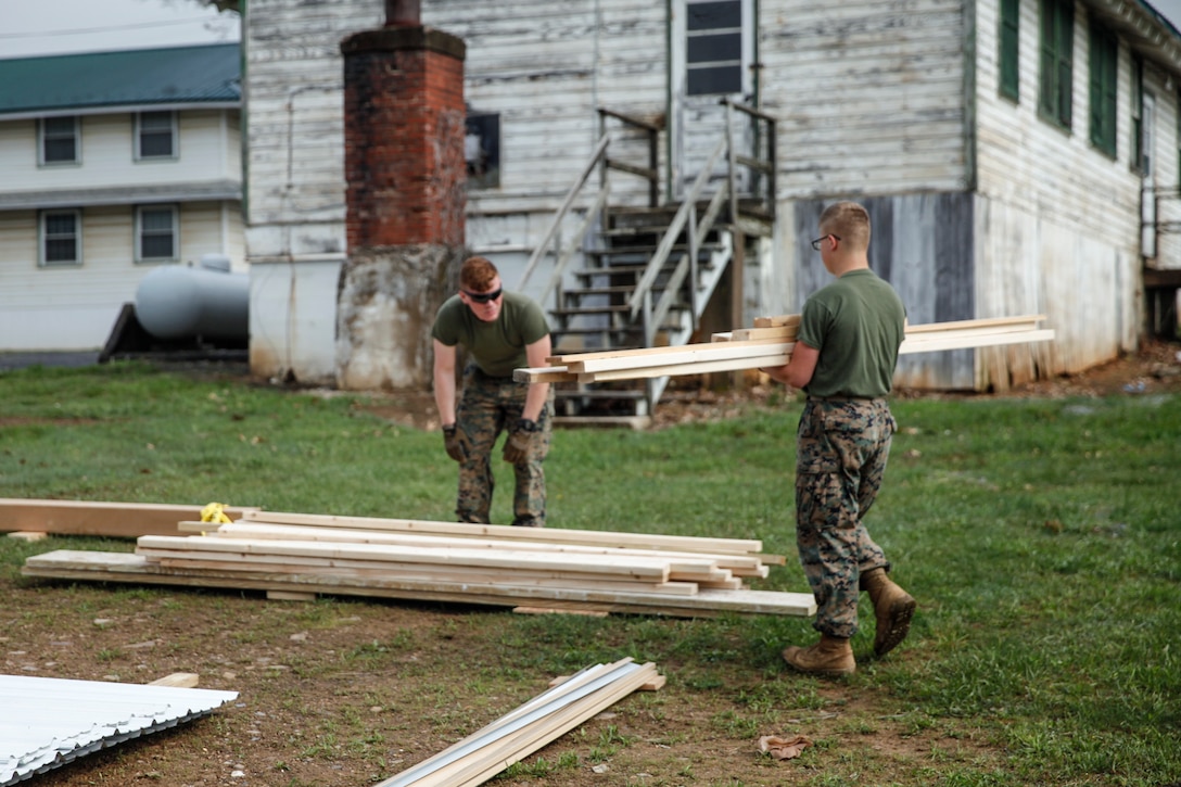 U.S. Marines Lance Cpl. Jason P. McWhinnie (left), field radio operator with Engineer Support Company, 6th Engineer Support Battalion, 4th Marine Logistics Group, and Private First Class Austin T. Roberts (right), combat engineer with Bridge Company C, 6th ESB, 4th MLG, gather and stack wooden planks at a construction site during exercise Red Dagger at Fort Indiantown Gap, Pa., May 20, 2018.