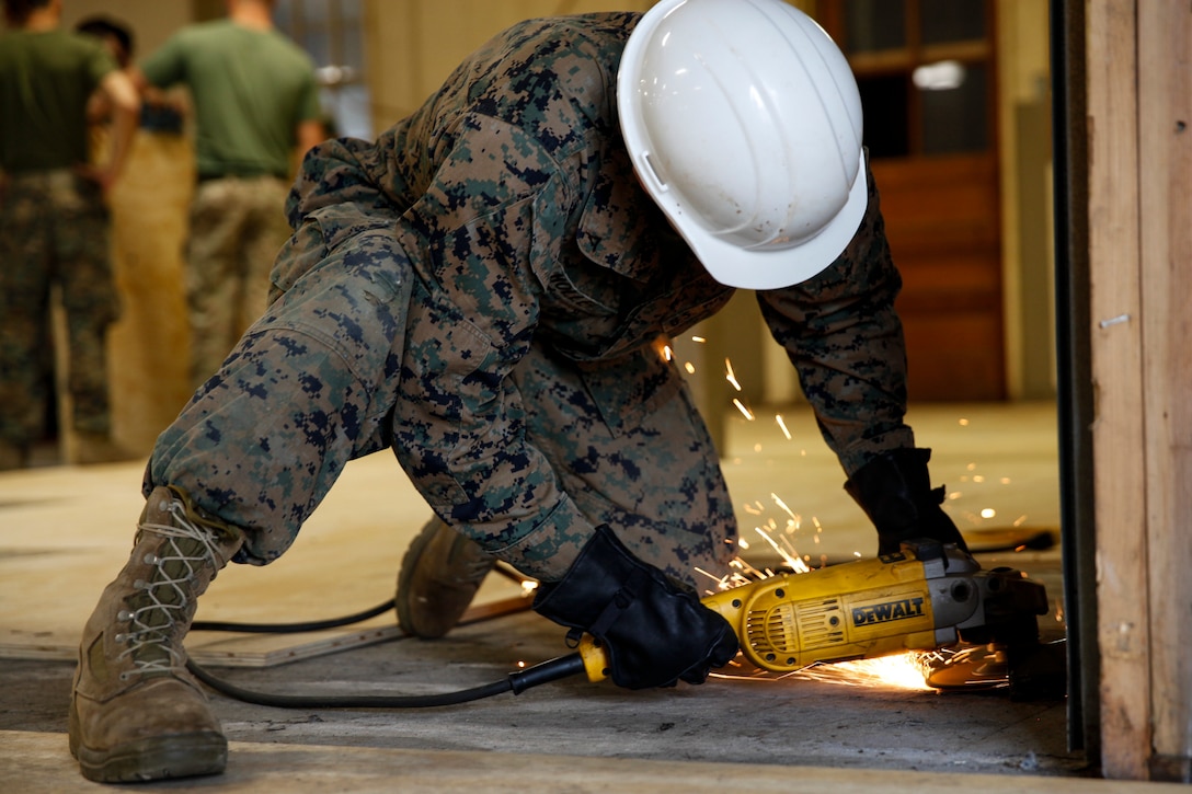 U.S. Marine Lance Cpl. Casey W. Holle, combat engineer with Engineer Company C, 6th Engineer Support Battalion, 4th Marine Logistics Group, uses a grinder to level the ground at a construction site during exercise Red Dagger at Fort Indiantown Gap, Pa., May 20, 2018.