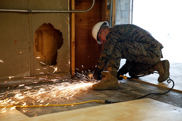 U.S. Marine Lance Cpl. Casey W. Holle, combat engineer with Engineer Company C, 6th Engineer Support Battalion, 4th Marine Logistics Group, uses a grinder to level the ground at a construction site during exercise Red Dagger at Fort Indiantown Gap, Pa., May 20, 2018.
