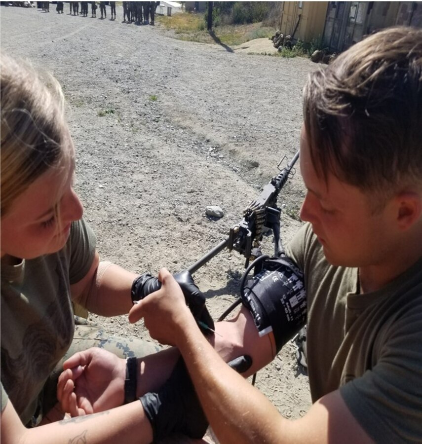 Lance Corporal Shivers of Alpha Company applies an IV on HM3 Ford in a Combat Lifesaving Class.