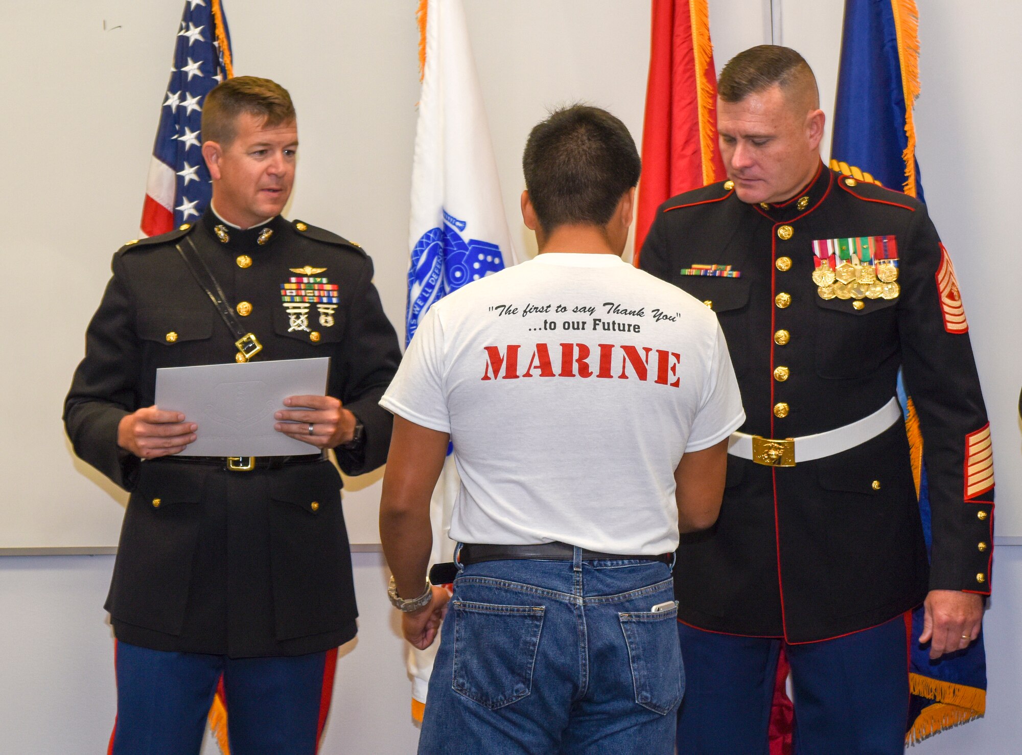 A Marine enlistee accepts his challenge coin and certificate from U.S. Marine Maj. Andrew Armstrong, Marine Corp Detachment commander, and Gunnery Sgt. Christopher Toten, Marine Corps Detachment senior enlisted leader during the Our Community Salutes ceremony San Angelo, Texas, May 19, 2018. The Marine Corps had eight enlistees, the most of the services represented. (U.S. Air Force photo by Aryn Lockhart/Released)