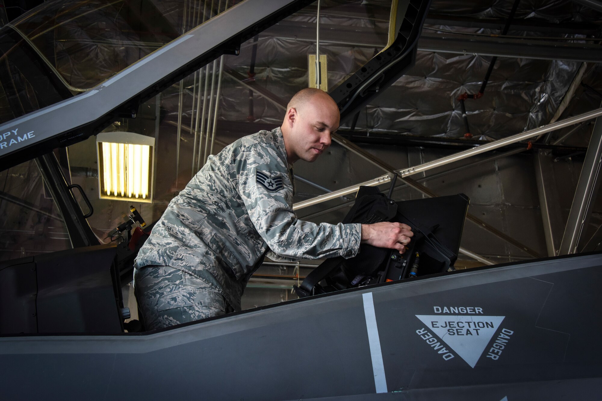 Staff Sgt. Nicholas Westover inspects the seatbelt of an F-35 Lightning II ejection seat structure