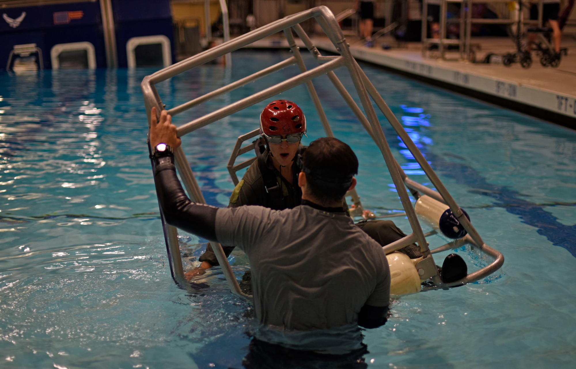 Nicole A. Mann, NASA astronaut, prepares to be flipped upside down by Survival Evasion Resistance and Escape specialists during a water survival course at Fairchild Air Force Base, Washington, May 18, 2018. One simulation that the NASA team completed during their stay at Fairchild, was the dunker course. Trainees are strapped inside a modular egress training system that simulates a mock helicopter with lap belts that submerges into water and rotates to teach aircrew how to find their exits to safety. (U.S. Air Force photo/Airman 1st Class Jesenia Landaverde)