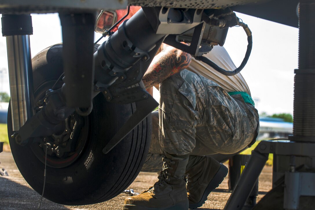 An airman changes the tire on a helicopter.