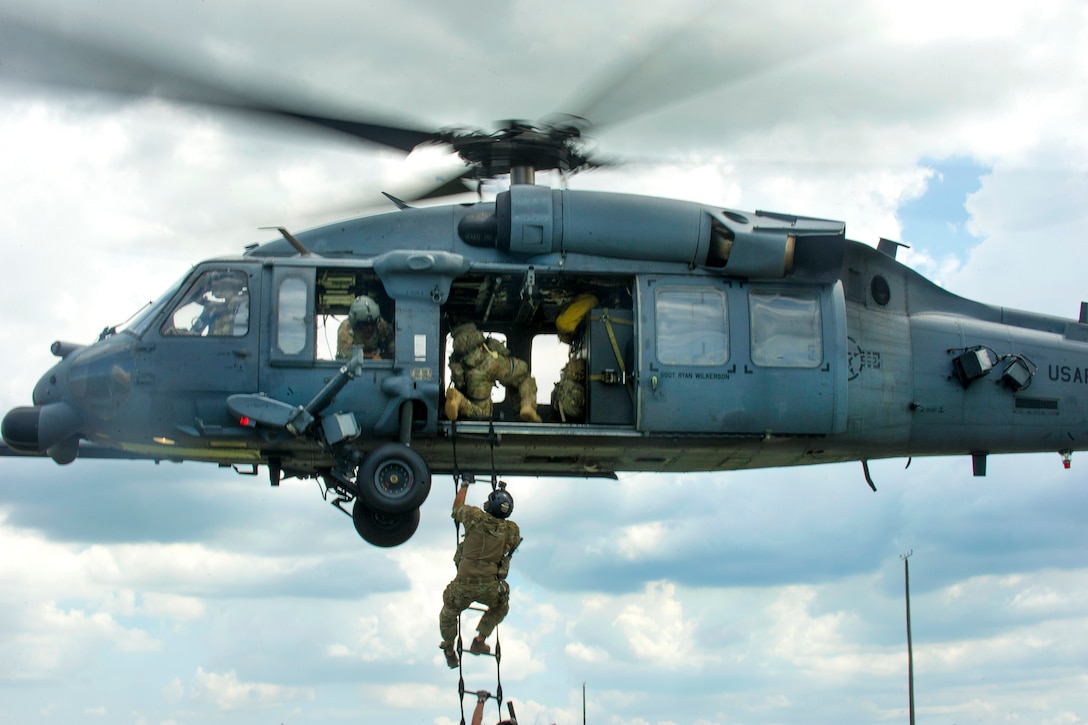 Airmen practice climbing a ladder into an HH-60 Pave Hawk helicopter.