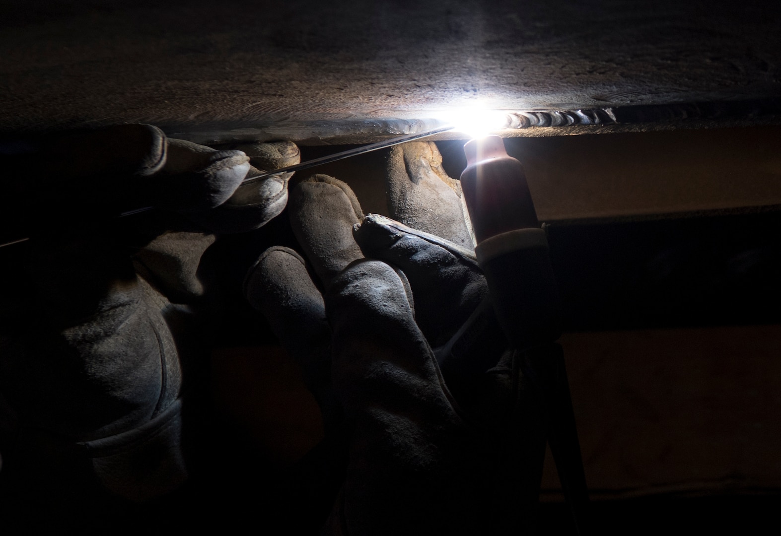 Mark Flannery, a welder from Detachment 6 at Al Udeid Air Base, Qatar, welds a steel plate to the bottom of a Jet Petroleum 8 tank in a vehicle management garage at an undisclosed location in Southwest Asia, April 27, 2018. Flannery was hand selected to come and repair the tank. (U.S. Air Force photo by Staff Sgt. Joshua King)