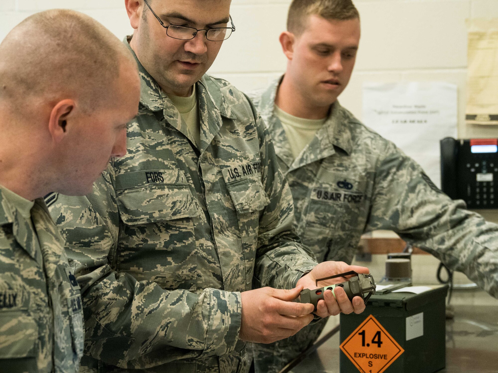 From left, Staff Sgt. Ryan Kelly, Tech. Sgt. Matthew Fors and Tech. Sgt. Brandon Carlson inspect stun grenades used by Security Forces. (Air Force Photo/Paul Zadach)