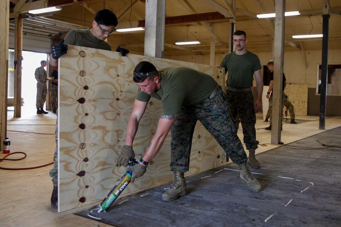 U.S. Marine Lance Cpl. Wesley C. Blankenship, combat engineer with Bridge Company C, 6th Engineer Support Battalion, 4th Marine Logistics Group, uses liquid nail glue before putting down a piece of plywood at a construction site during exercise Red Dagger at Fort Indiantown Gap, Pa., May 21, 2018.