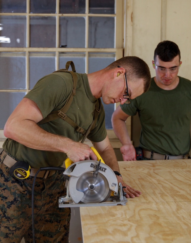 U.S. Marines Lance Cpl. Ryan A. Leenarts (left), combat engineer with Engineer Company C, 6th Engineer Support Battalion, 4th Marine Logistics Group, uses a circular saw to cut a piece of plywood as Lance Cpl. Jacob N. Wooldridge (right), combat engineer with Bridge Company C, 6th ESB, 4th MLG, holds the wood in place at a construction site during exercise Red Dagger at Fort Indiantown Gap, Pa., May 21, 2018.