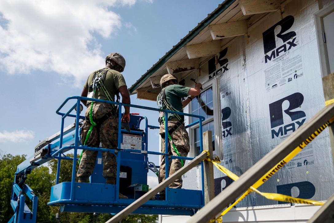 British Army Spr. John Rees (right), commando with 131 Commando Squadron Royal Engineers, British Army, hammers a nail in a window frame as U.S. Marine Lance Cpl. Jerricko L. Willins (left), combat engineer with Bridge Company C, 6th Engineer Support Battalion, 4th Marine Logistics Group, operates the boom lift that they are using for height at a construction site during exercise Red Dagger at Fort Indiantown Gap, Pa., May 21, 2018.