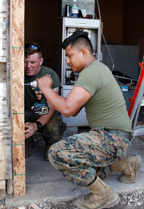 U.S. Marine Lance Cpl. Luis A. Eufraciodolores (right), administrative clerk with Headquarters and Service Company, 6th Engineer Support Battalion, 4th Marine Logistics Group, uses a drill to screw in a door frame as Lance Cpl. Jason P. McWhinnie (left), field radio operator with Engineer Support Company, 6th ESB, 4th MLG, helps hold the frame in place at a construction site during exercise Red Dagger at Fort Indiantown Gap, Pa., May 21, 2018.