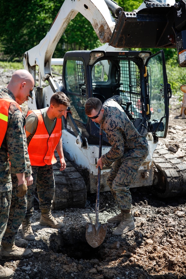 U.S. Marine Lance Cpl. Mitchell R. Neimann (left), heavy equipment operator with Engineer Company C, 6th Engineer Support Battalion, 4th Marine Logistics Group, digs a hole at a construction site during exercise Red Dagger at Fort Indiantown Gap, Pa., May 21, 2018. Exercise Red Dagger is a bilateral training exercise that gives Marines an opportunity to exchange tactics, techniques and procedures as well as build working relationships with their British counterparts. (U.S. Marine Corps photo by Sgt. Melanie Wolf/Released)